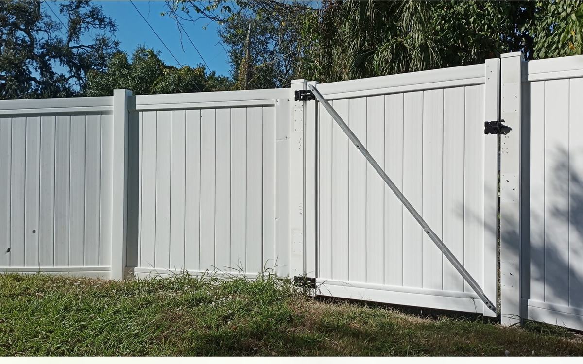 The same vinyl fence run and braced gate, uniform white after Sandbar soft washing