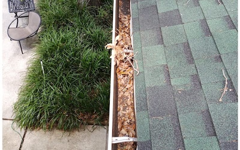 Aluminum gutter packed with leaves and debris before Sandbar gutter cleaning — real job photo