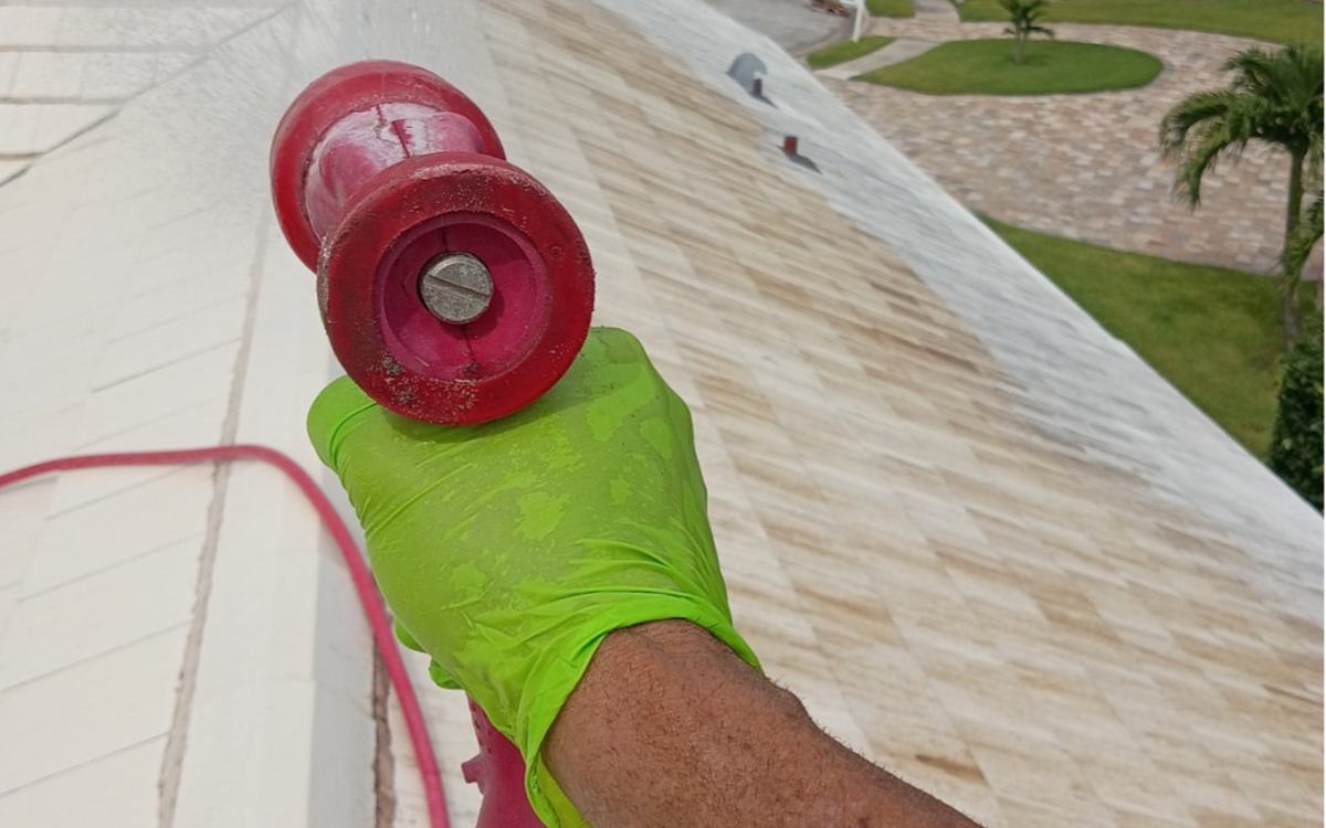 Sandbar crew member rinsing a white roof during a soft wash — real job photo